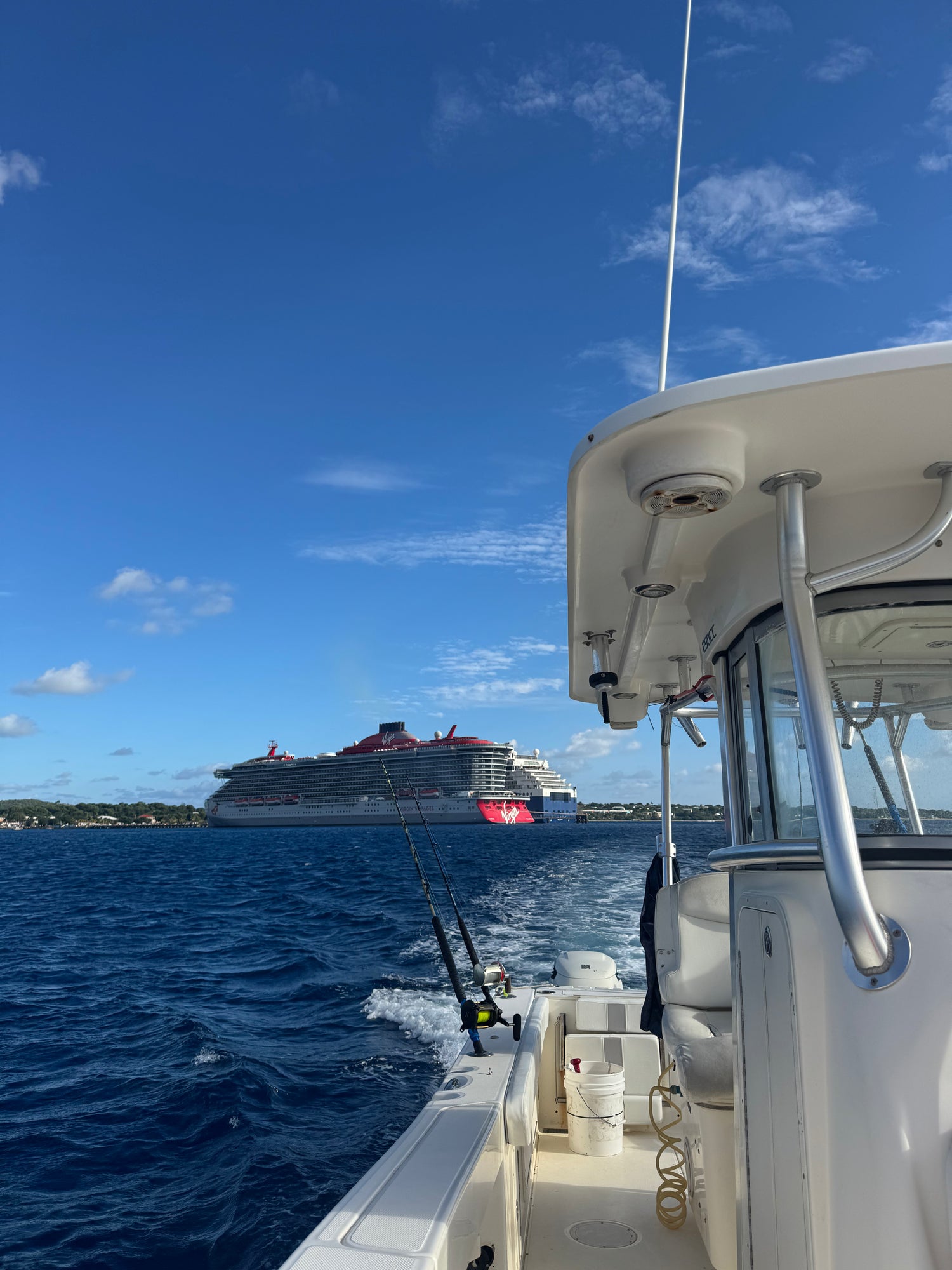 Fishing boat on the water with 2 cruise ships (Virgin Voyages and Celebrity Cruise) in the background