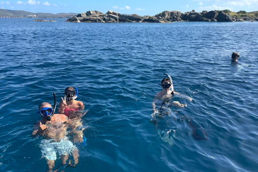 Snorkelers in clear blue water with rocky St.croix islands in the background
