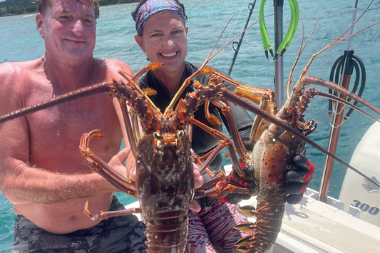 Two people holding a large lobster on a boat with water in the background. St.Croix Spearfishing Charter 2 Lobsters