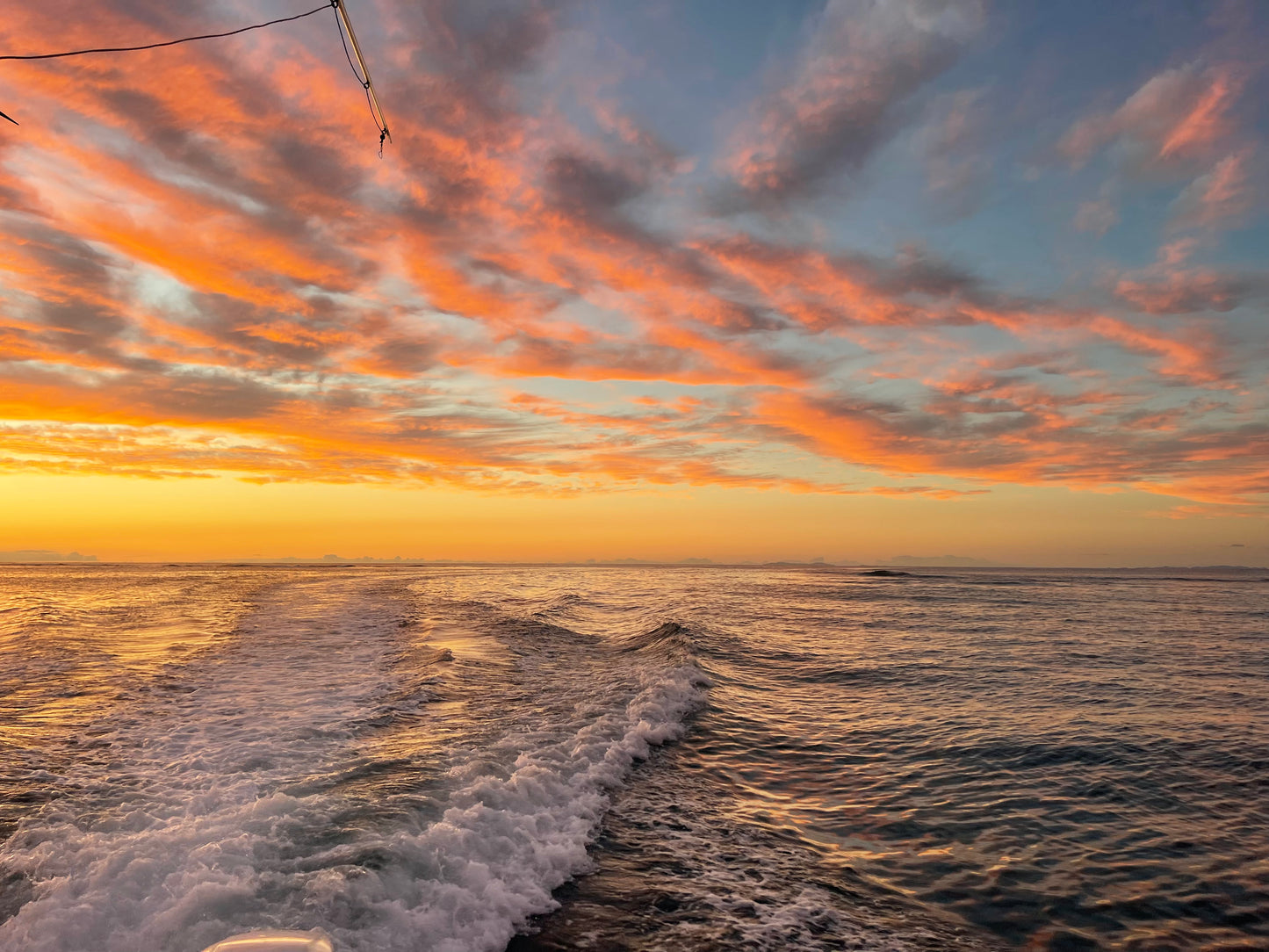 Sunset over the ocean with colorful clouds and boat wake. St.Croix Sunset Sail Charter