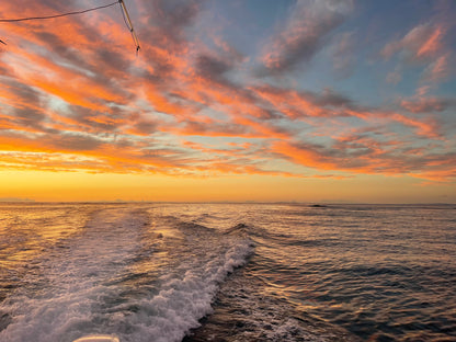 Sunset over the ocean with colorful clouds and boat wake. St.Croix Sunset Sail Charter
